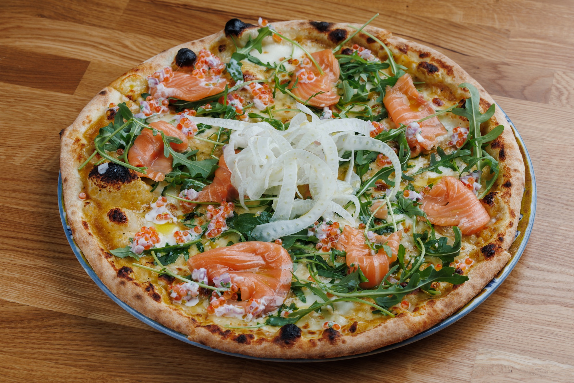 Pizza gialla con rucola, salmone, salsa al caviale e finocchio